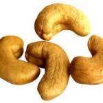 Four roasted cashew nuts arranged on a white surface.