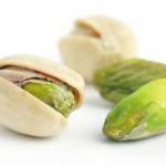 Three pistachio nuts, one open with a green kernel visible.
