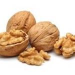 Whole and cracked walnuts with pieces of walnut kernel on a white background.